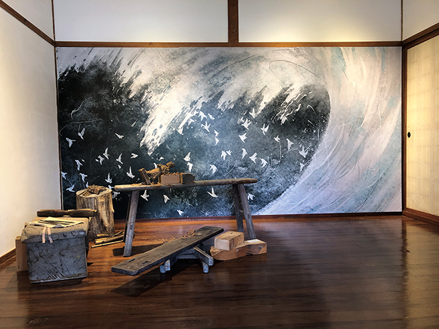 第一展場重現真實的木雕場景，搭配相關原作以大幅水墨畫作輸出，讓四、五○年代花蓮的山風海雨情境躍然眼前。